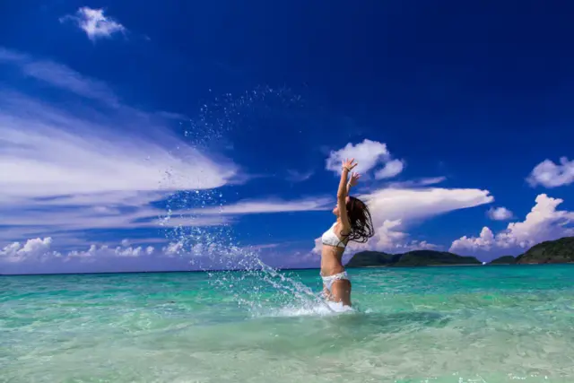 海の中で水しぶきを上げて楽しむ女性。