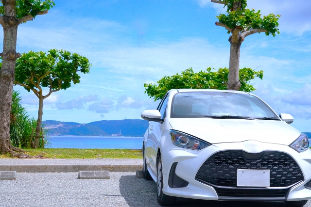海沿いの駐車場に停まる白い乗用車。