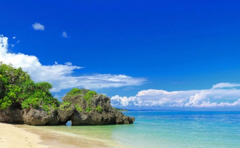 青空と透き通った海、岩場がある石垣島の白い砂浜。